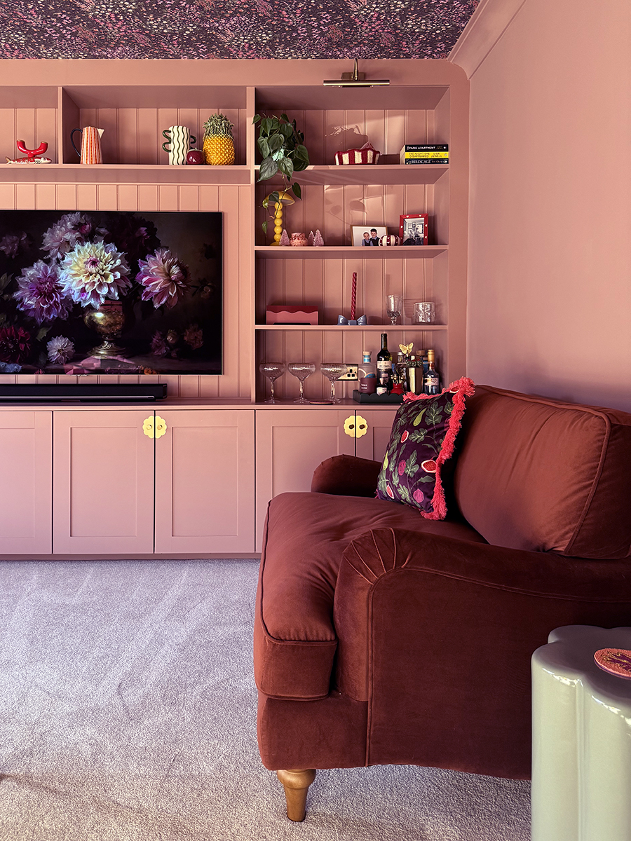 blush pink built-in cupboards with cherry red velvet loveseat and soft cream carpet